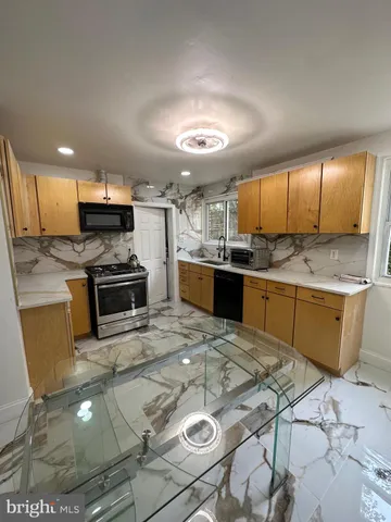 a kitchen with stainless steel appliances kitchen island granite countertop a sink stove and cabinets