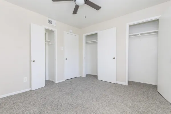 an empty room with chandelier fan and windows