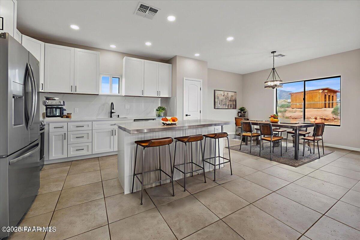 320 South Hoss Road Dewey, AZ 86327 - Photo 10 of 42 a kitchen with stainless steel appliances granite countertop a stove top oven a sink a dining table and chairs with white cabinets