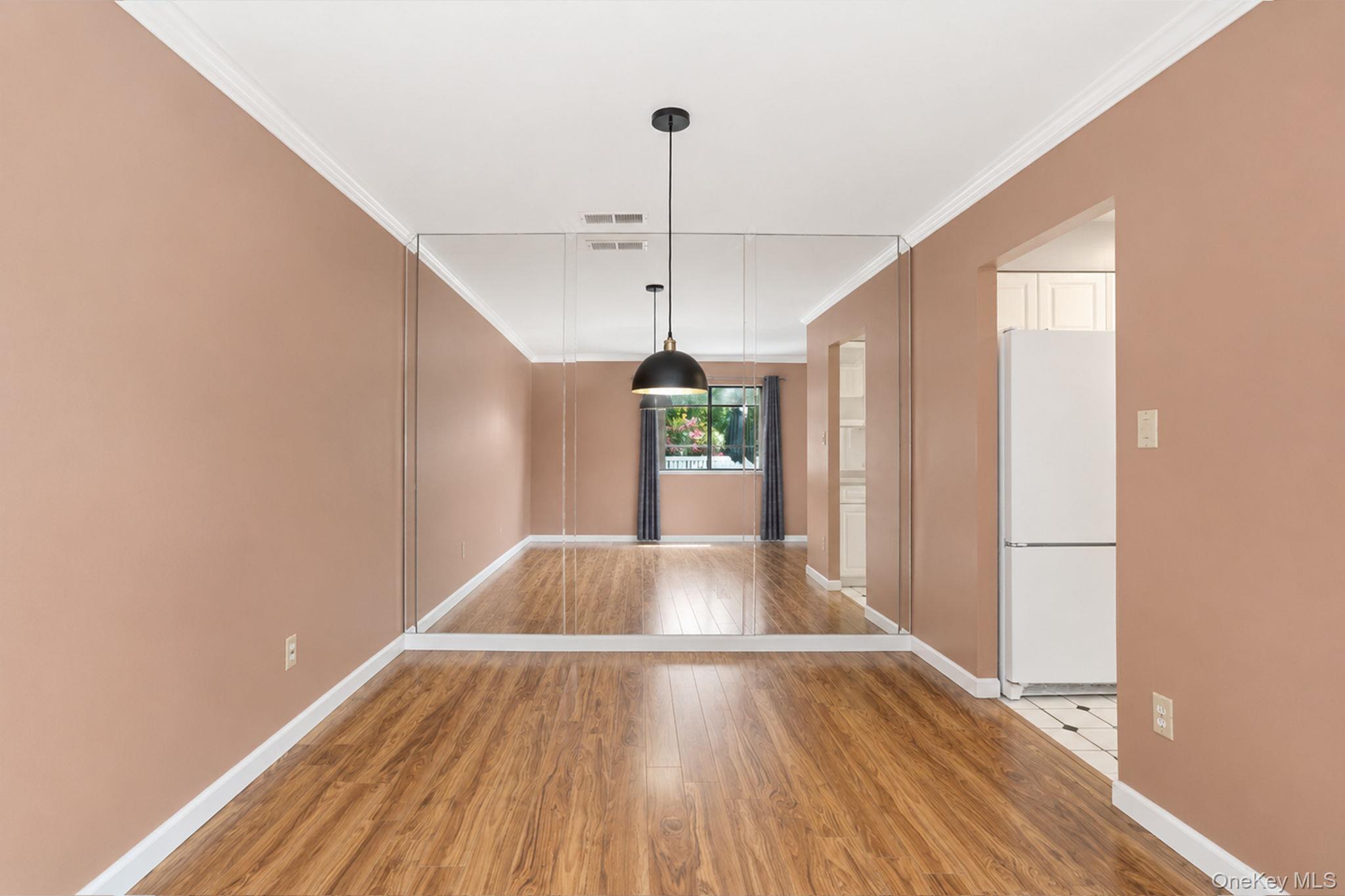 94 Birchwood Road Coram, NY 11727 - Photo 25 of 34 Dining room with laminate wood style flooring featuring a floor to ceiling full wall glass mirror.