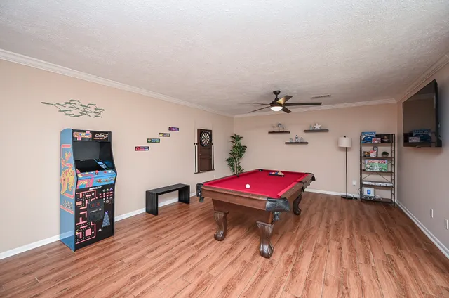 a living room with furniture pool table and wooden floor