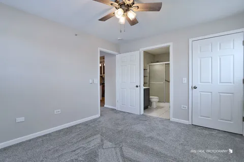 an empty room with a chandelier fan and closet area