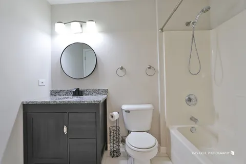 a bathroom with a granite countertop toilet sink mirror and vanity