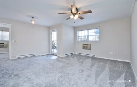 an empty room with windows and fan