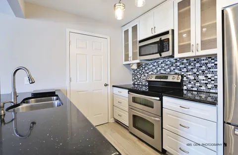 a kitchen with granite countertop white cabinets and stainless steel appliances