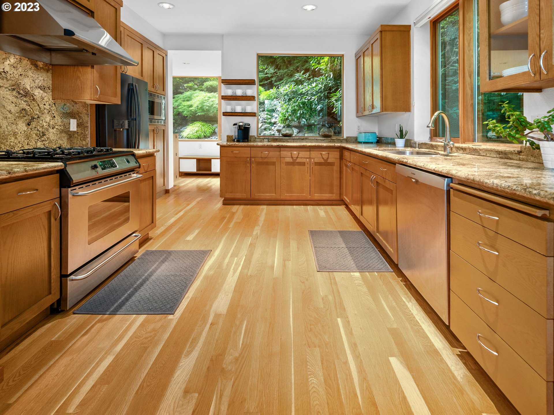 3727 Southwest Condor Lane Portland, OR 97239 - Photo 8 of 33 a view of a kitchen with kitchen island a large window cabinets a sink and stainless steel appliances