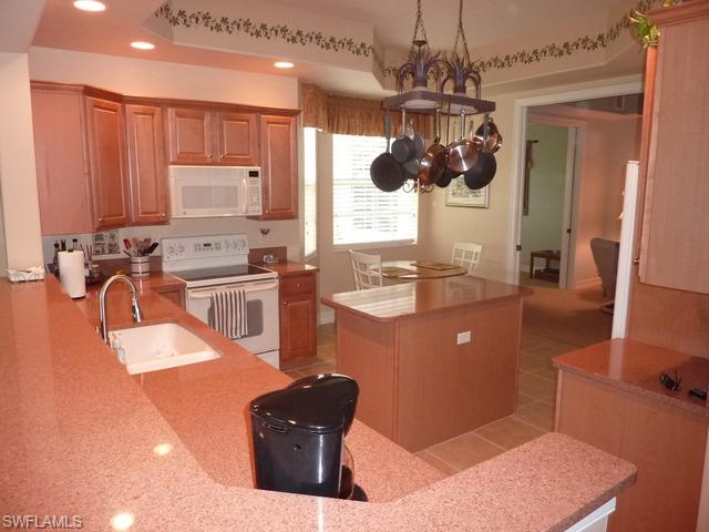 8613 Champions Point, Unit 302 Naples, FL 34113 - Photo 8 of 10 a kitchen with stainless steel appliances granite countertop a sink a stove and a wooden cabinets