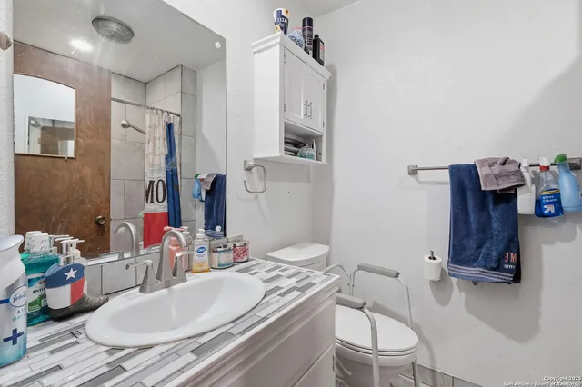 a bathroom with a granite countertop sink mirror vanity and toilet