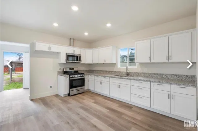 a kitchen with granite countertop white cabinets and stainless steel appliances