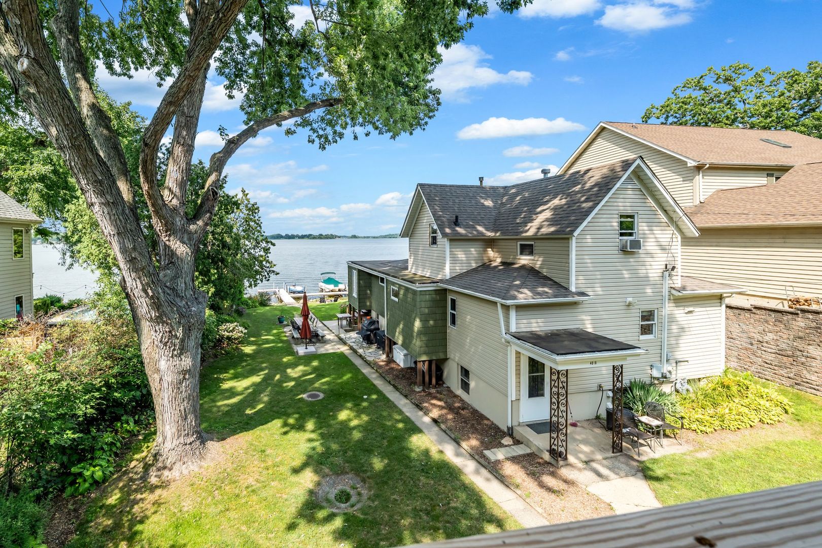 4018 Pitzen Road Johnsburg, IL 60051 - Photo 34 of 47 a view of a white house next to a yard with plants and large trees