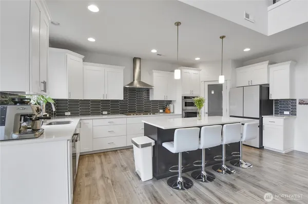 a kitchen with stainless steel appliances kitchen island granite countertop a wooden floor and white cabinets