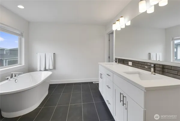 a bathroom with a double vanity sink a mirror and a bathtub