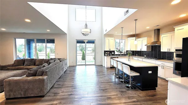 a living room with kitchen island granite countertop wooden floor a couch and a large window
