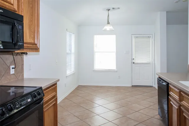 a view of an empty room with wooden floor and a ceiling fan