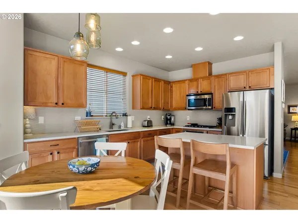 a kitchen with stainless steel appliances granite countertop a sink a stove a refrigerator cabinets and chairs
