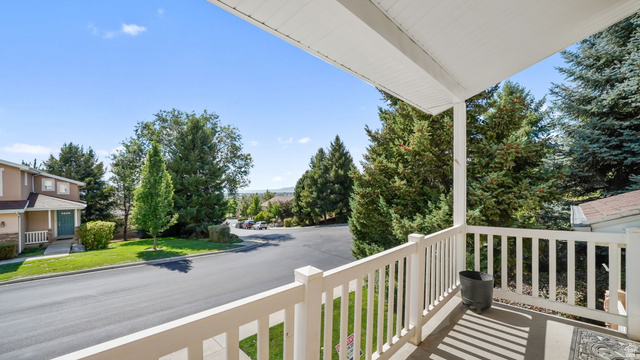 1285 Alpine Way Provo, UT 84606 - Photo 15 of 25 Covered porch with white railings, offering an elevated perspective of the street and surrounding mature trees