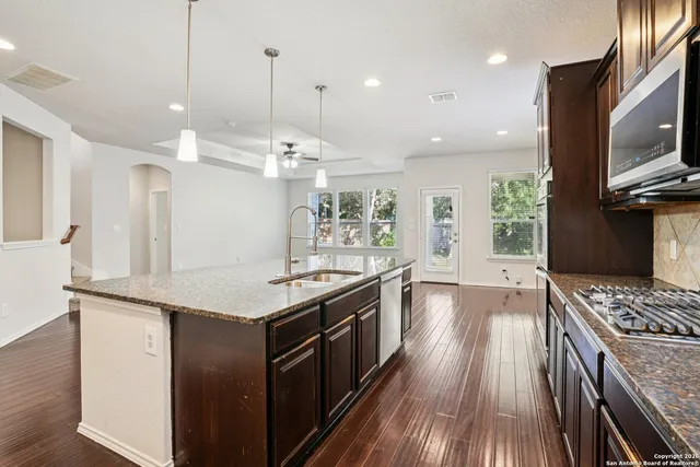 a kitchen with stainless steel appliances granite countertop a stove and a wooden floors