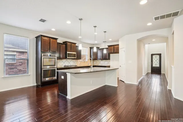 a kitchen with stainless steel appliances kitchen island granite countertop a stove a sink and a refrigerator