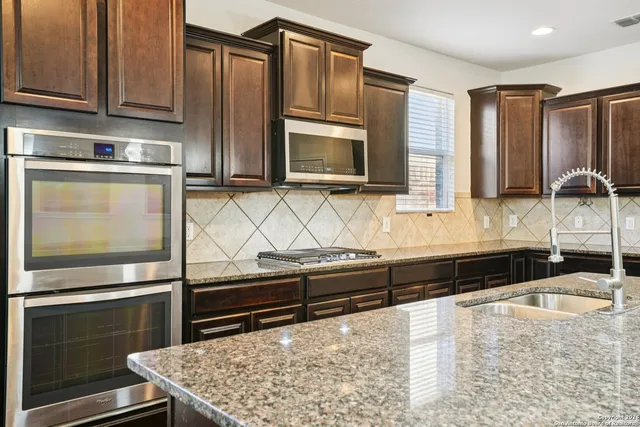a kitchen with granite countertop wooden cabinets and stainless steel appliances