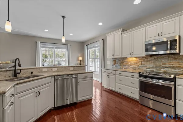 a kitchen with cabinets stainless steel appliances and wooden floor