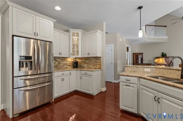 a kitchen with kitchen island a refrigerator a stove a sink dishwasher a oven with white cabinets and wooden floor