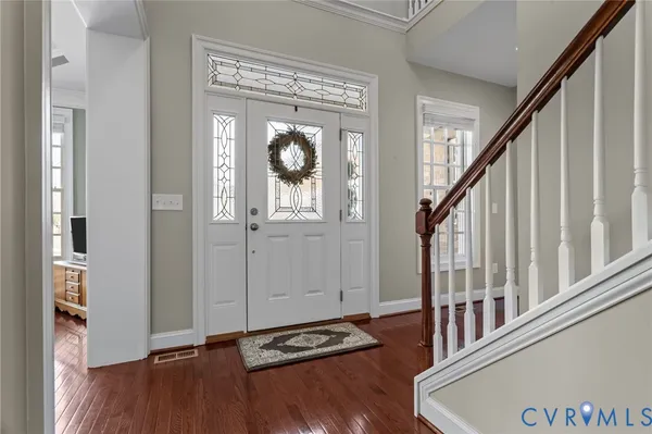 a view of an entryway with wooden floor and a kitchen view