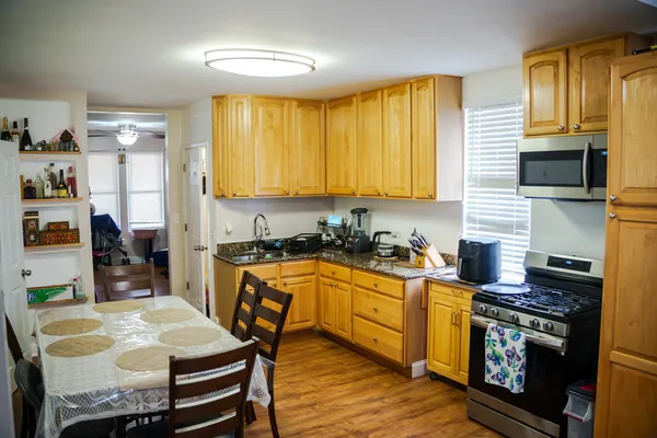 a kitchen with stainless steel appliances granite countertop a stove top oven a sink a dining table and chairs