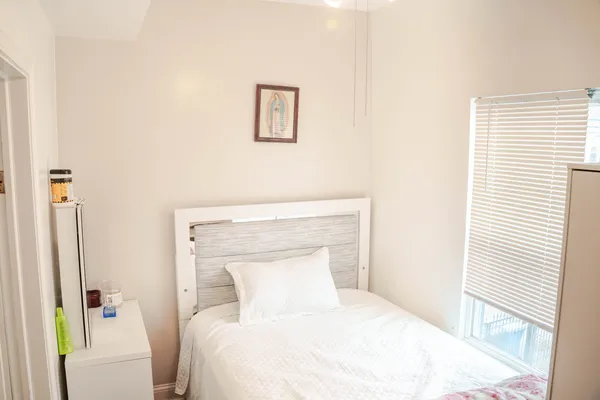 a bedroom with a white bed and a painting on the wall
