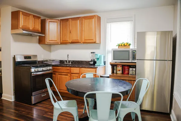 a kitchen with stainless steel appliances granite countertop a dining table chairs refrigerator and sink