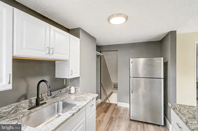 a kitchen with stainless steel appliances granite countertop a refrigerator sink and white cabinets