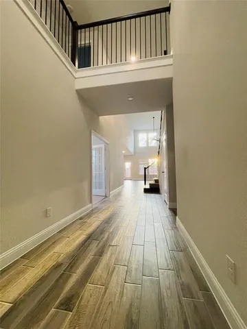 a view of a hallway with wooden floor and a bathroom