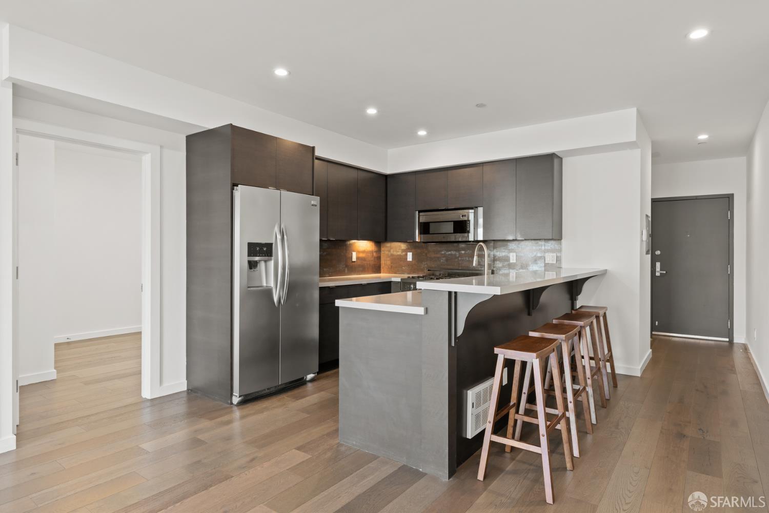252 9th Street, Unit 503 San Francisco, CA 94103 - Photo 3 of 15 a kitchen with kitchen island wooden cabinets and stainless steel appliances