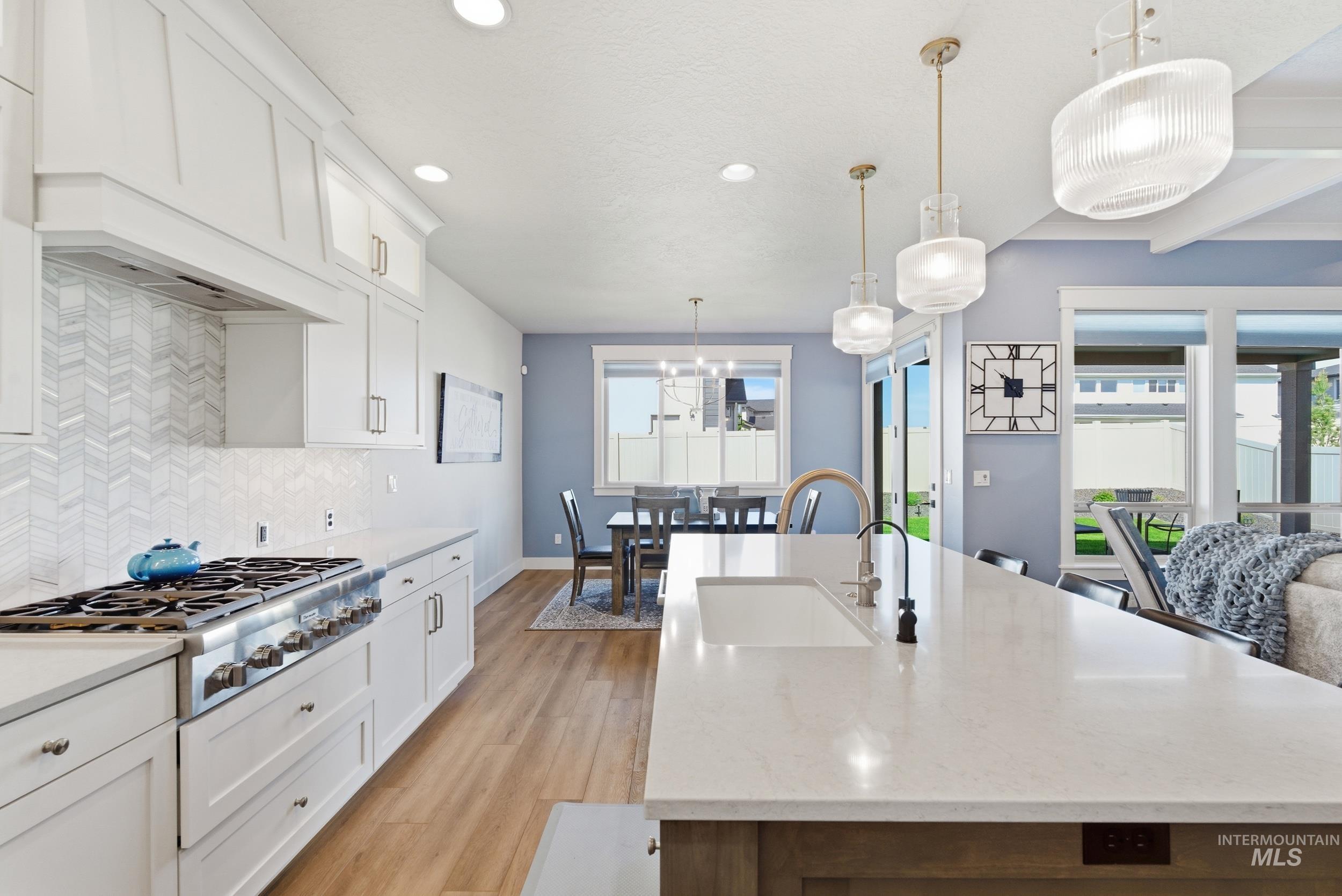 6347 South Utmost Lane Meridian, ID 83642 - Photo 8 of 37 Modern kitchen with a large central island featuring an undermount sink and contemporary pendant lighting