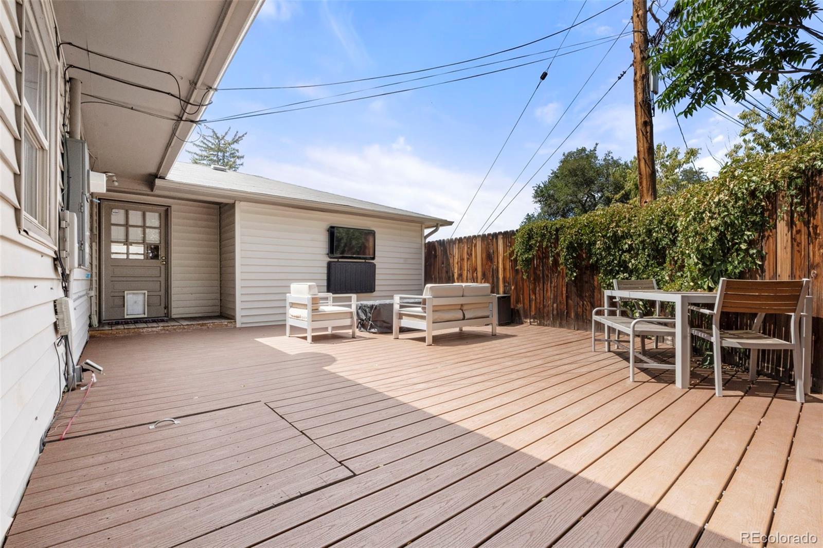 1845 South Mabry Way Denver, CO 80219 - Photo 15 of 20 a view of a patio with dining table and chairs with wooden floor and fence