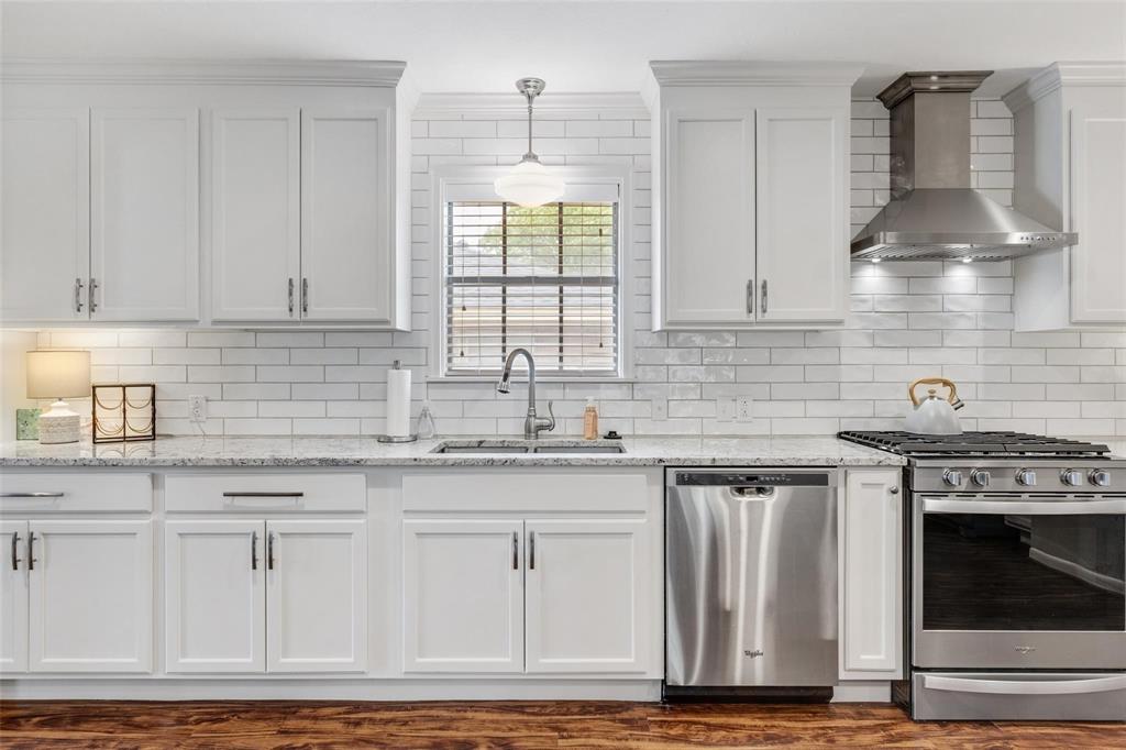 a kitchen with stainless steel appliances granite countertop a stove a sink and white cabinets