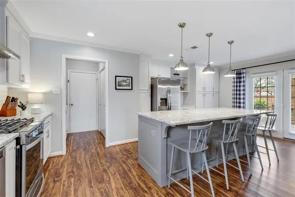 a kitchen with granite countertop a table chairs stove and wooden floor