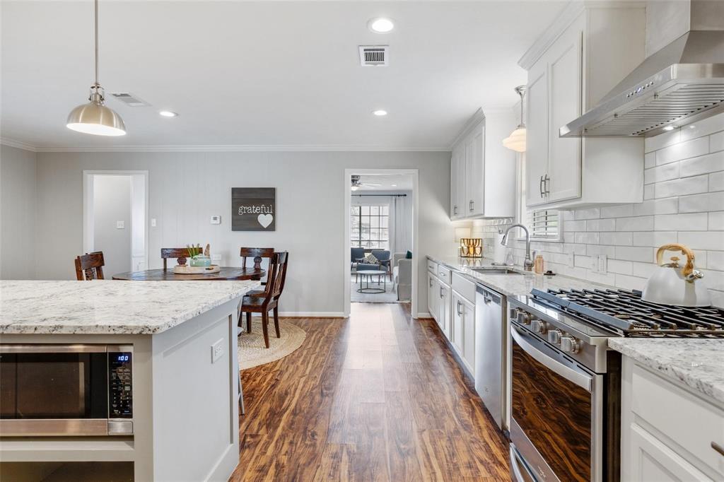 607 West Cedar Street Celina, TX 75009 - Photo 5 of 26 a kitchen with stainless steel appliances granite countertop a stove top oven a sink dishwasher and a refrigerator with wooden floor