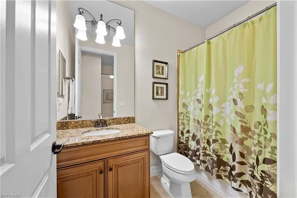 a bathroom with a granite countertop sink a toilet and a mirror
