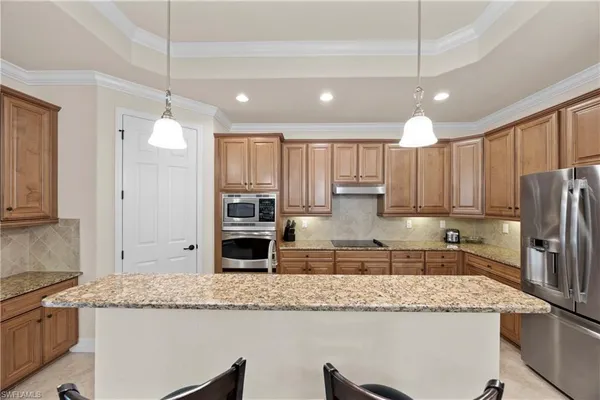 a kitchen with granite countertop a refrigerator a stove a sink cabinets and a refrigerator