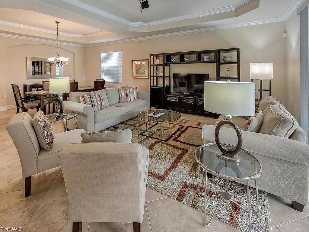 9254 Veneto Place Naples, FL 34113 - Photo 10 of 30 Living room with a chandelier, crown molding, a raised ceiling, and light tile patterned floors