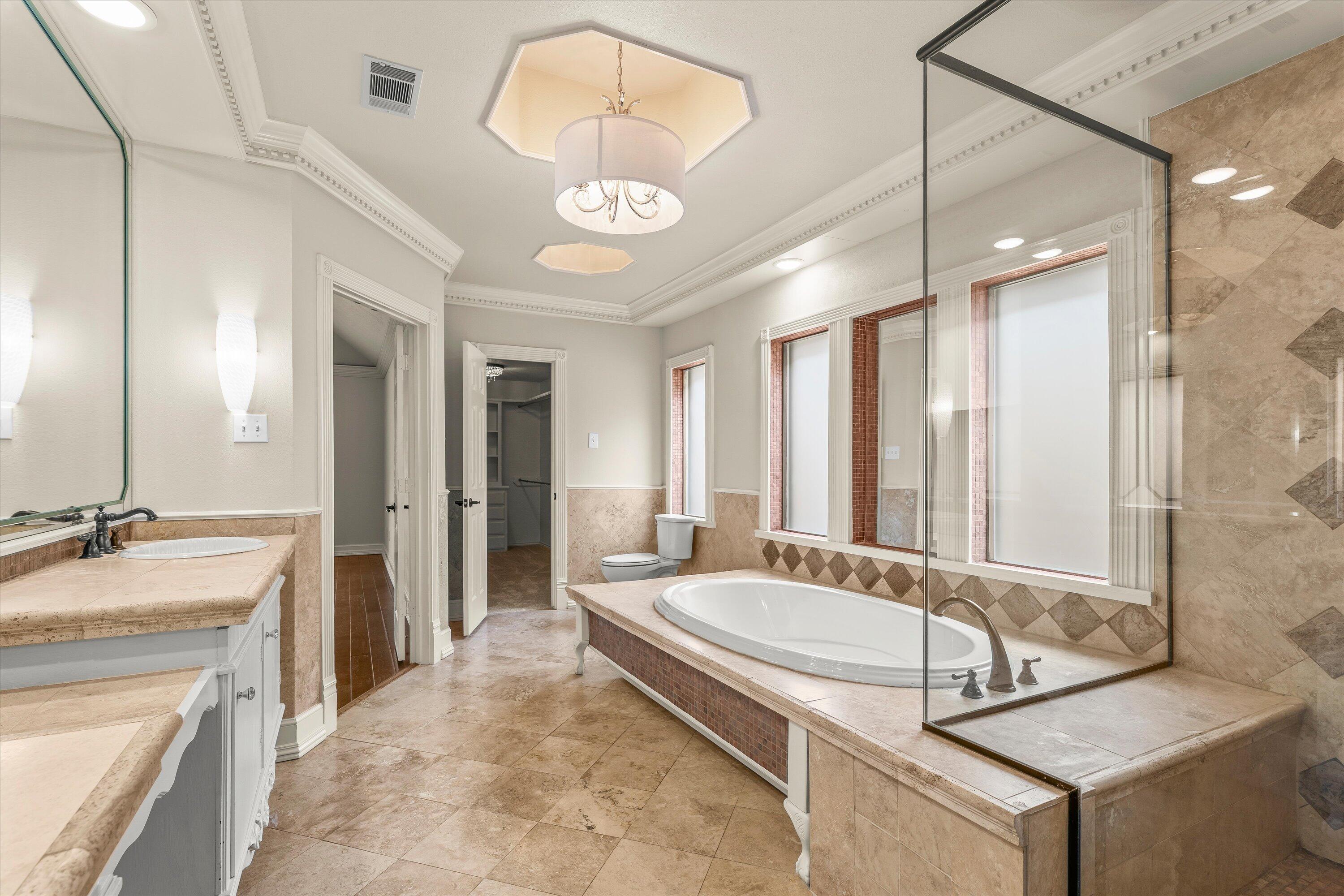 5110 96th Street Lubbock, TX 79424 - Photo 23 of 50 a spacious bathroom with a granite countertop tub sink and mirror