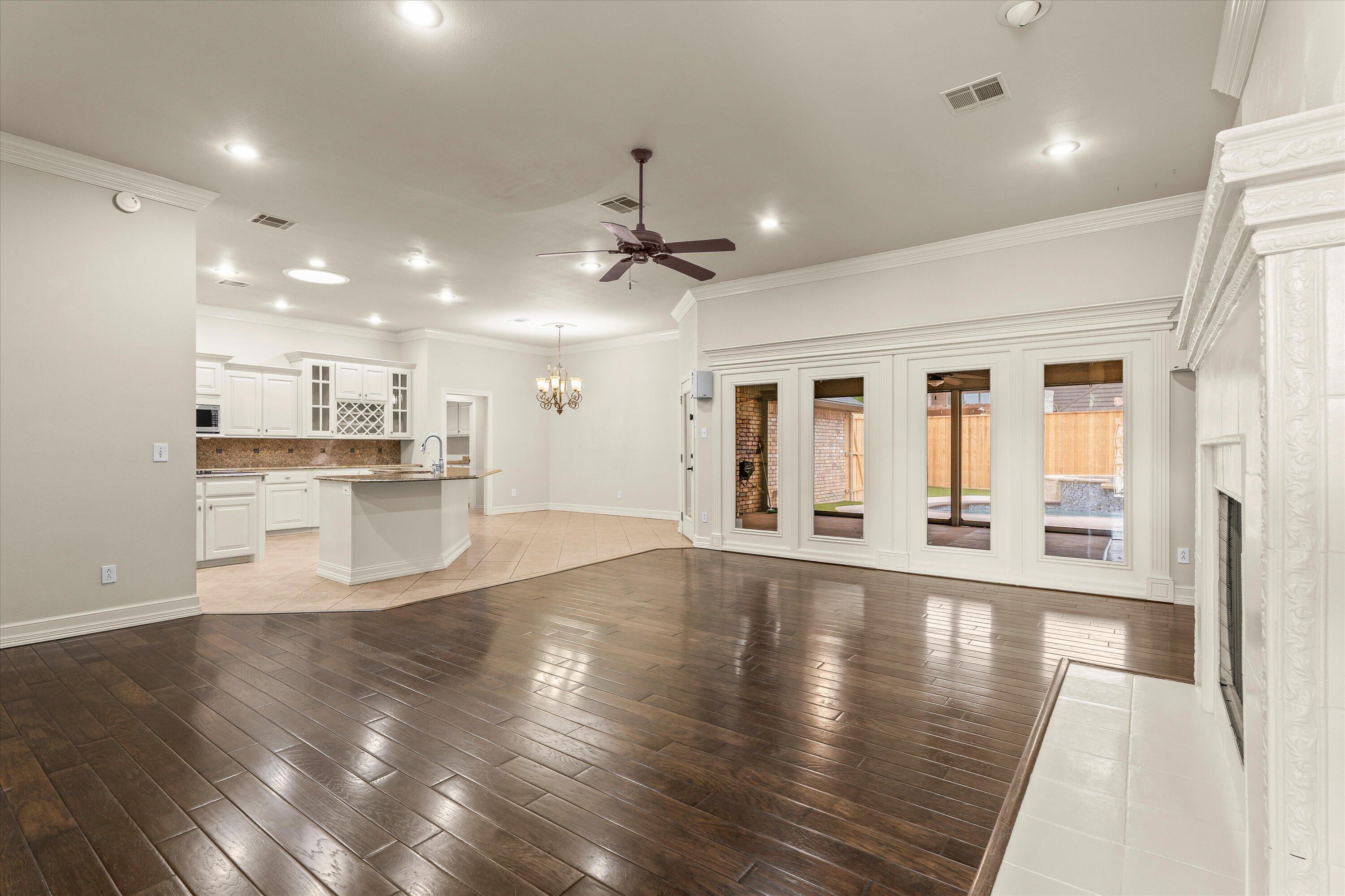 5110 96th Street Lubbock, TX 79424 - Photo 5 of 50 a view of an empty room with wooden floor and a kitchen