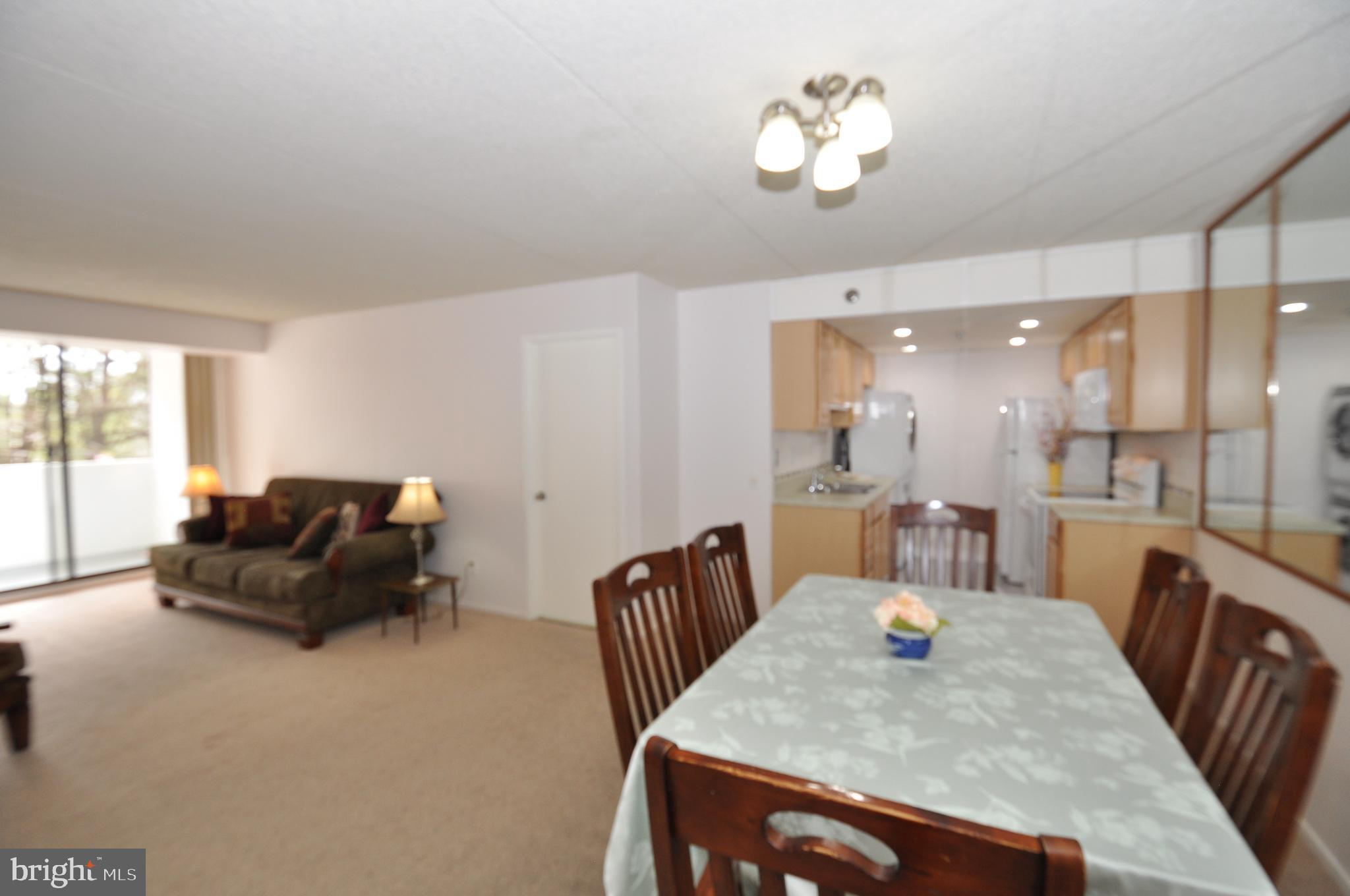 5911 Edsall Road, Unit 403 Alexandria, VA 22304 - Photo 4 of 29 a living room with furniture a chandelier and a dining table