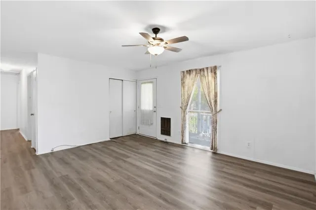 a view of an empty room with wooden floor and a window