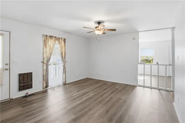 an empty room with wooden floor and windows