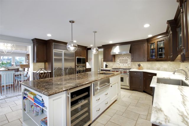 a kitchen with stainless steel appliances granite countertop a sink a stove and a wooden cabinets