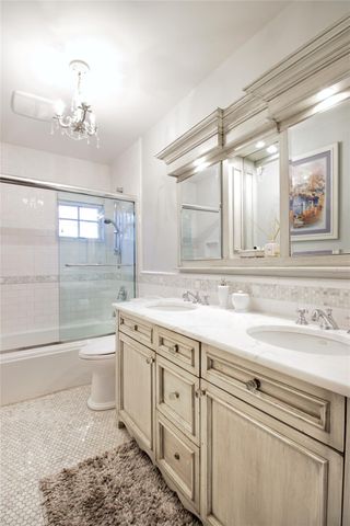 a bathroom with a granite countertop sink a large mirror a bathtub and next to a window