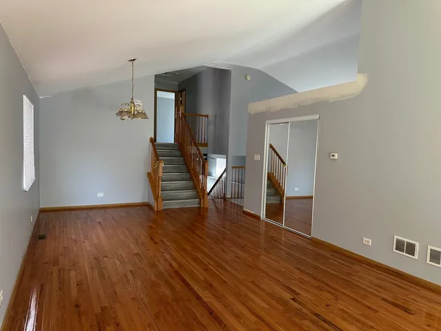 a view of an empty room with wooden floor and stairs