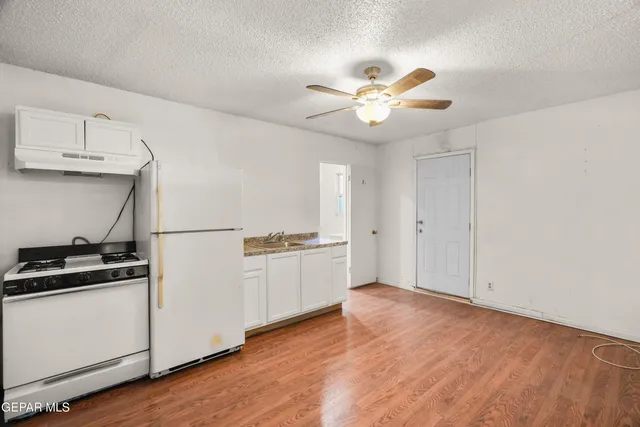 a kitchen with granite countertop a refrigerator a stove a microwave and white cabinets