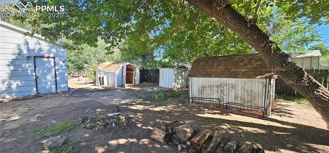a backyard of a house with large trees and barbeque